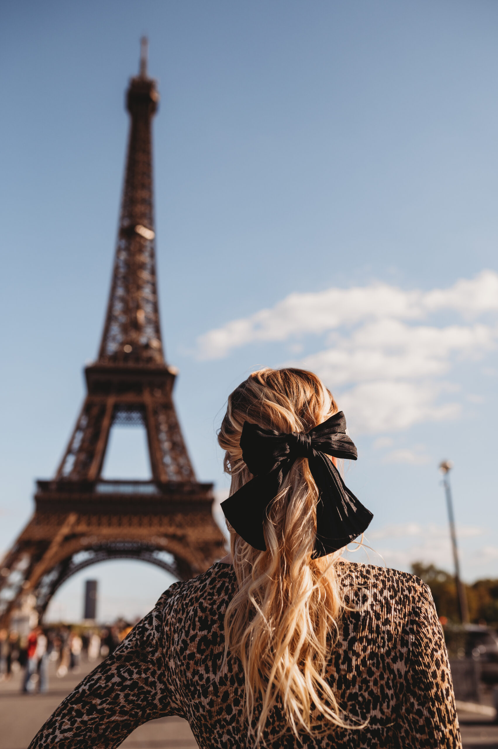 Woman standing in front of the Eiffel Tower in Paris, captured by Liberty Photography — an empowering portrait celebrating feminine strength and self-expression.
